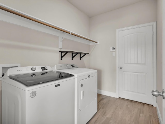 washroom with washing machine and clothes dryer and light hardwood / wood-style floors