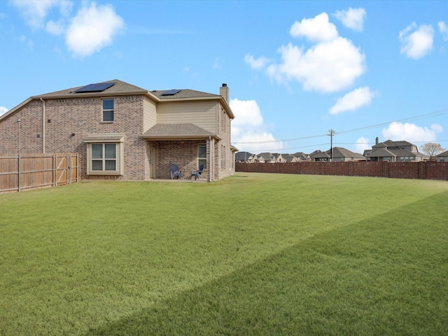 rear view of property with a yard and solar panels