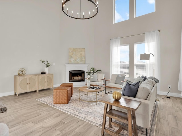 living room with an inviting chandelier, light hardwood / wood-style floors, and a high ceiling