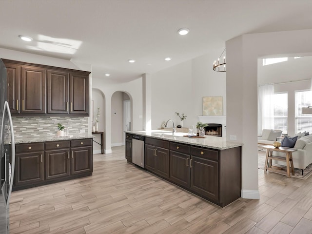 kitchen with light stone countertops, sink, dishwasher, and dark brown cabinets