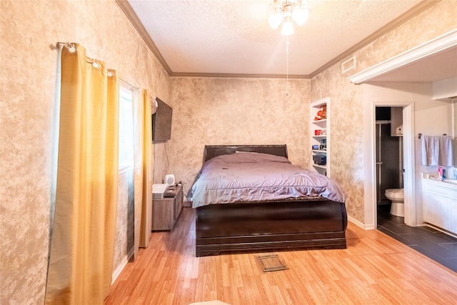 bedroom with hardwood / wood-style floors, ensuite bathroom, ornamental molding, and a textured ceiling