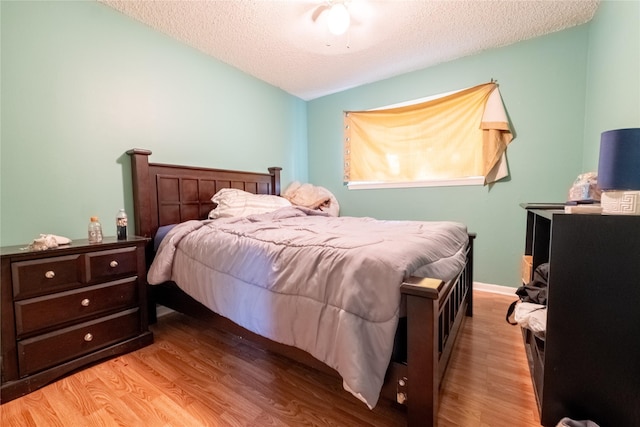 bedroom featuring a textured ceiling, light hardwood / wood-style flooring, and lofted ceiling