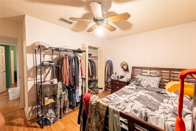 bedroom with light wood-type flooring, a textured ceiling, and ceiling fan