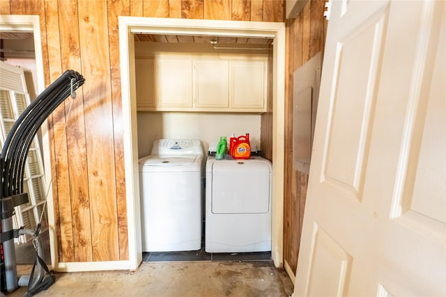 laundry area with cabinets, washer and dryer, and wooden walls