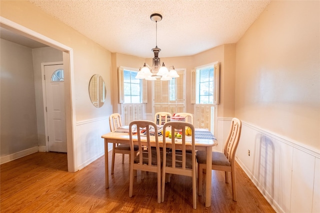 dining space with hardwood / wood-style flooring, plenty of natural light, a textured ceiling, and a notable chandelier