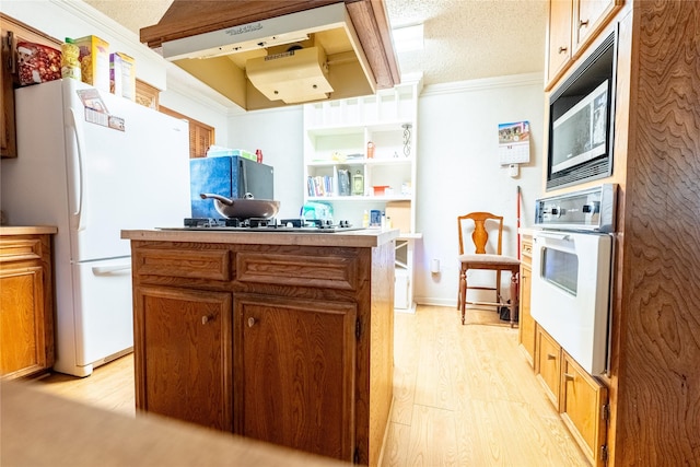 kitchen featuring a center island, white appliances, crown molding, light wood-type flooring, and a textured ceiling