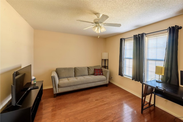 living room with dark hardwood / wood-style floors, ceiling fan, and a textured ceiling