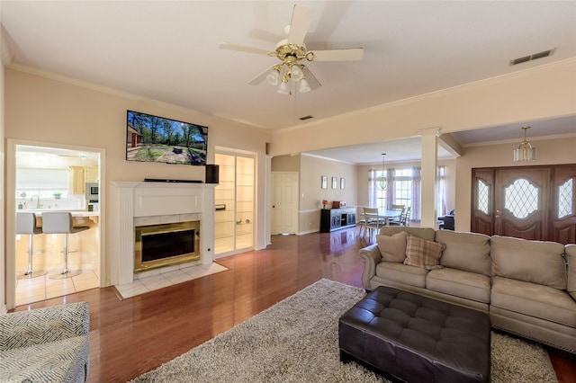 living room with hardwood / wood-style flooring, ceiling fan, crown molding, and a fireplace