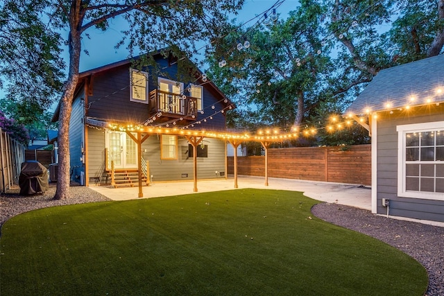 rear view of property featuring a patio, a balcony, and a lawn