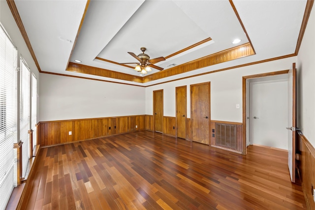 empty room with a raised ceiling, ceiling fan, and dark hardwood / wood-style floors