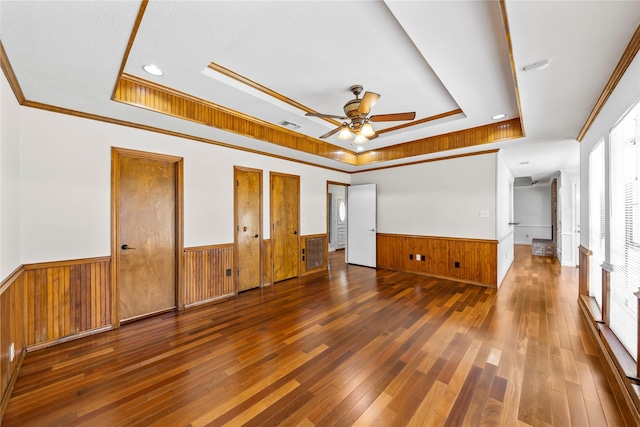 unfurnished room with dark hardwood / wood-style flooring, a tray ceiling, ceiling fan, and ornamental molding