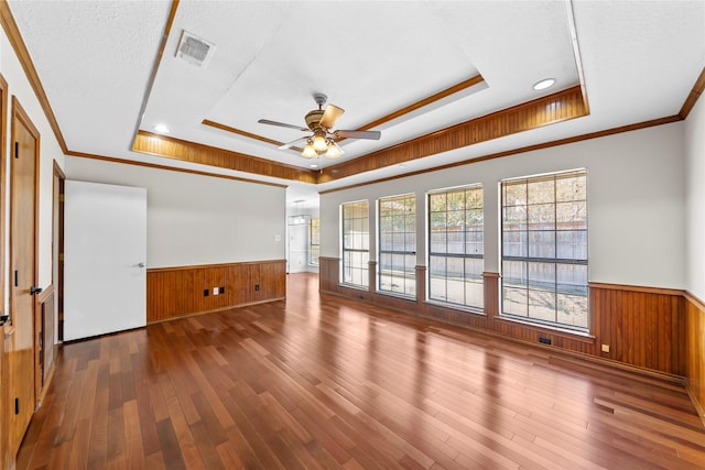 unfurnished living room featuring a textured ceiling, a tray ceiling, ceiling fan, and dark wood-type flooring