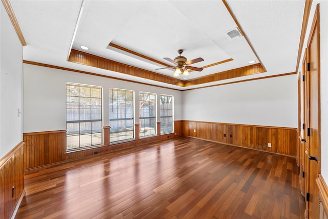 spare room featuring ceiling fan, dark hardwood / wood-style floors, a raised ceiling, and crown molding