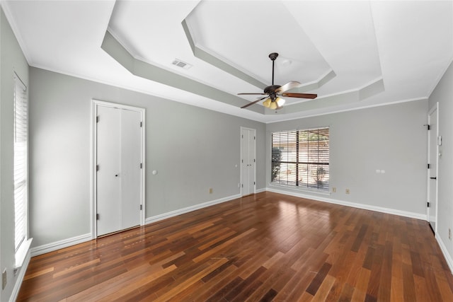 unfurnished room featuring a tray ceiling, ceiling fan, dark hardwood / wood-style flooring, and crown molding