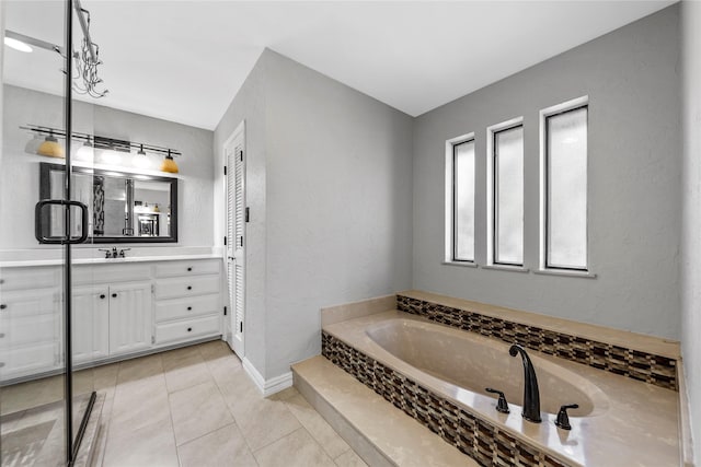 bathroom with tile patterned flooring, vanity, and a relaxing tiled tub