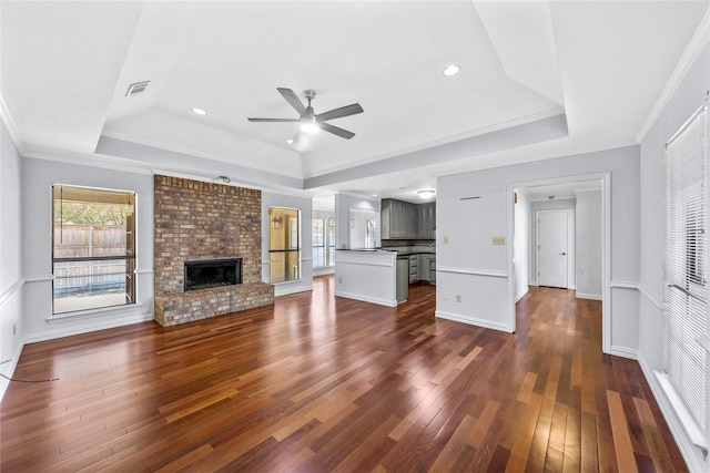 unfurnished living room featuring ceiling fan, ornamental molding, a fireplace, and a tray ceiling