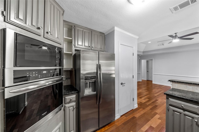 kitchen with gray cabinetry, dark hardwood / wood-style floors, ceiling fan, dark stone countertops, and appliances with stainless steel finishes