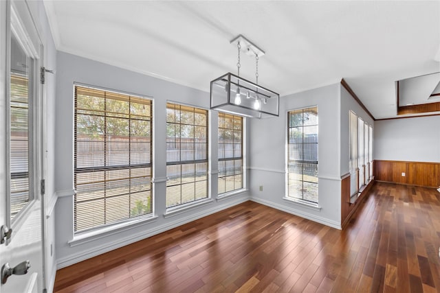 unfurnished dining area with dark hardwood / wood-style flooring, crown molding, and a notable chandelier