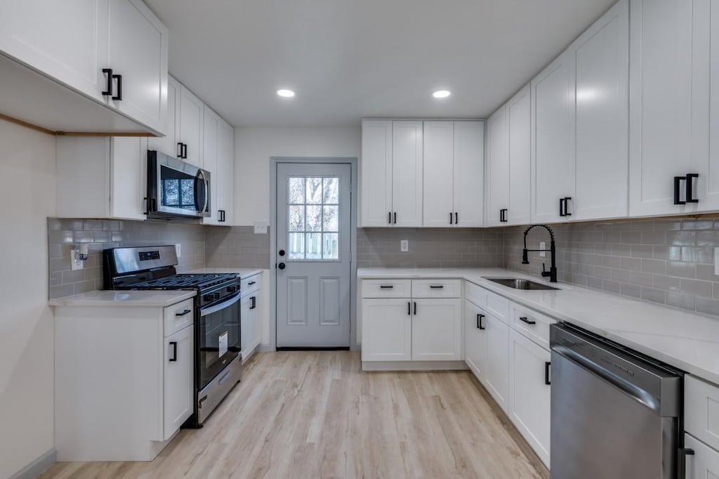 kitchen featuring white cabinets, sink, appliances with stainless steel finishes, and tasteful backsplash