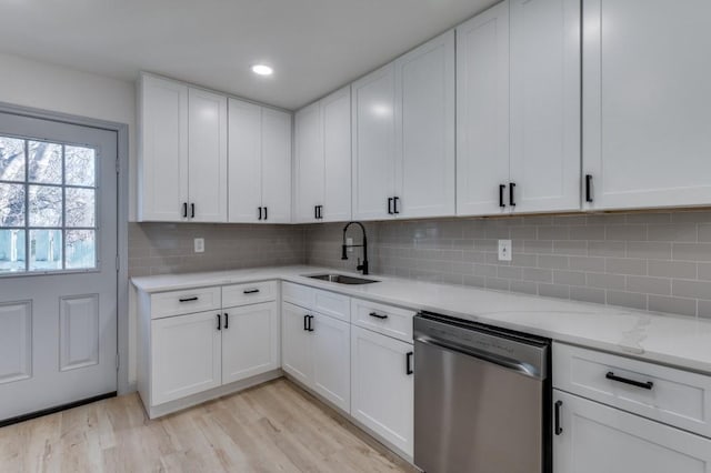 kitchen featuring stainless steel dishwasher, white cabinets, sink, and tasteful backsplash