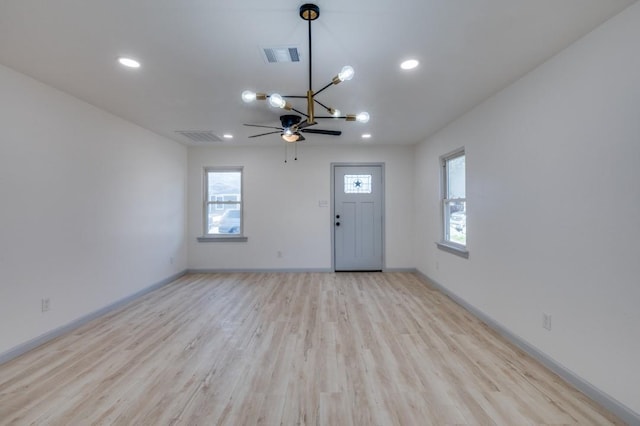 interior space with a healthy amount of sunlight, light wood-type flooring, and an inviting chandelier