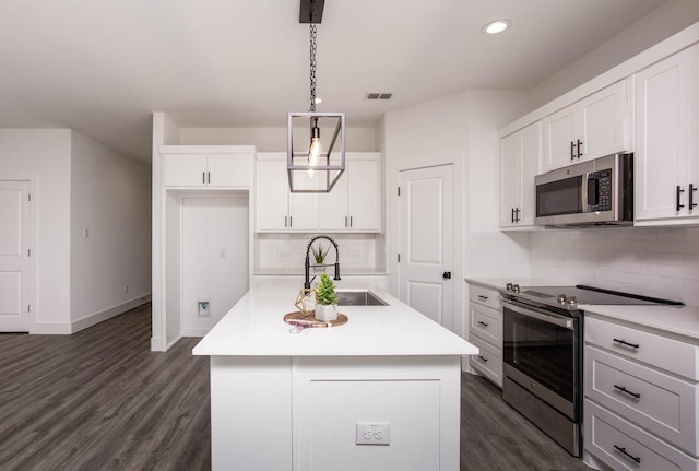 kitchen with a center island with sink, white cabinets, sink, appliances with stainless steel finishes, and decorative light fixtures