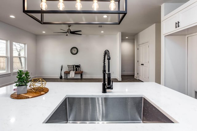 kitchen with white cabinetry, ceiling fan, sink, light stone countertops, and decorative light fixtures