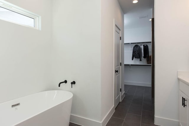 bathroom with tile patterned floors, a washtub, and vanity