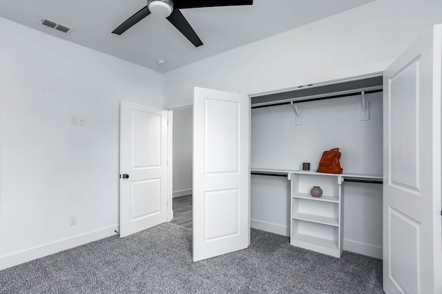 unfurnished bedroom with dark colored carpet, ceiling fan, and a closet