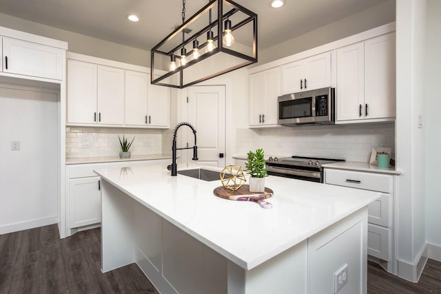 kitchen featuring sink, stainless steel appliances, white cabinetry, and an island with sink