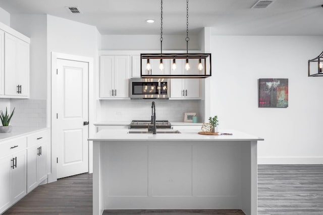 kitchen with decorative light fixtures, white cabinetry, decorative backsplash, and a kitchen island with sink