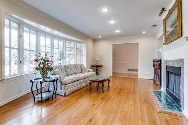 living room featuring crown molding, a fireplace, and light hardwood / wood-style flooring