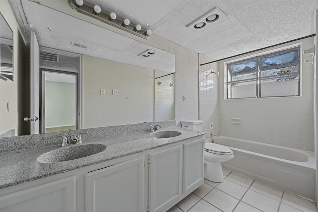 full bathroom featuring tiled shower / bath combo, tile patterned flooring, a textured ceiling, toilet, and vanity