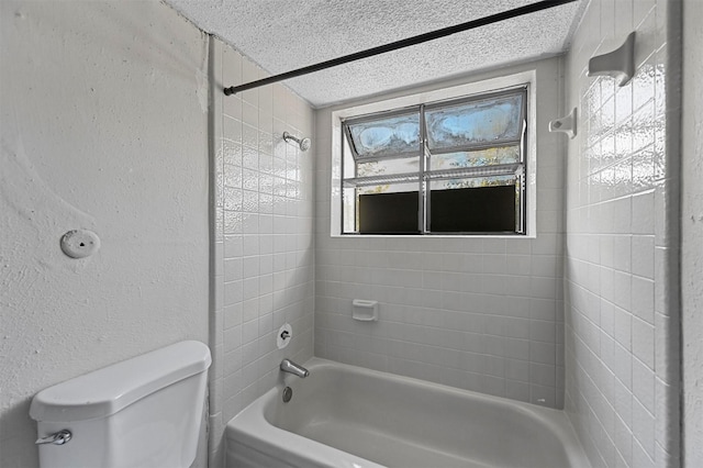 bathroom with a wealth of natural light, toilet, a textured ceiling, and tiled shower / bath