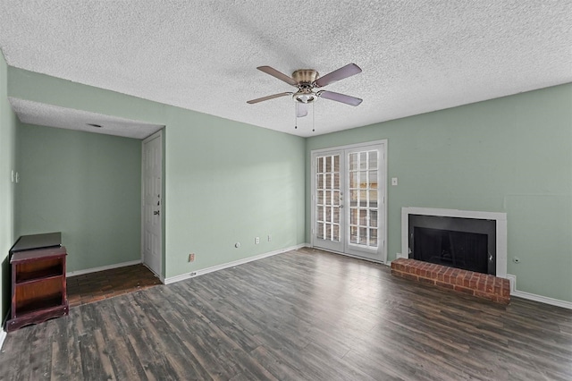 unfurnished living room featuring ceiling fan, french doors, dark hardwood / wood-style floors, a textured ceiling, and a fireplace