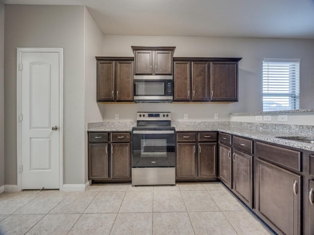 kitchen with light stone countertops, dark brown cabinets, and appliances with stainless steel finishes