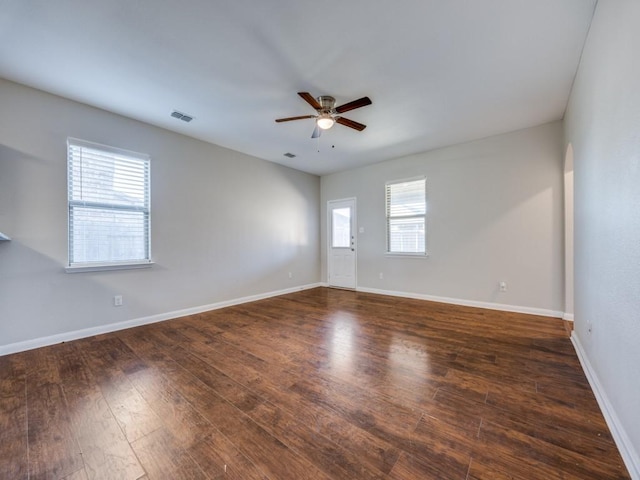 empty room featuring dark hardwood / wood-style flooring, ceiling fan, and plenty of natural light