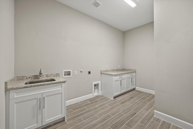 clothes washing area with cabinets, electric dryer hookup, light hardwood / wood-style floors, washer hookup, and sink