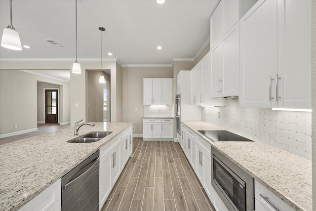 kitchen with decorative light fixtures, white cabinetry, stainless steel appliances, sink, and light stone counters