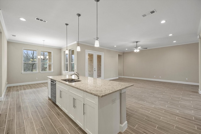 kitchen featuring decorative light fixtures, sink, white cabinetry, an island with sink, and ceiling fan with notable chandelier