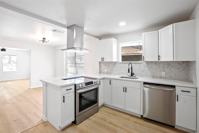 kitchen with stainless steel appliances, white cabinets, island range hood, and sink