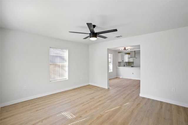 unfurnished living room featuring sink, ceiling fan, and light hardwood / wood-style flooring