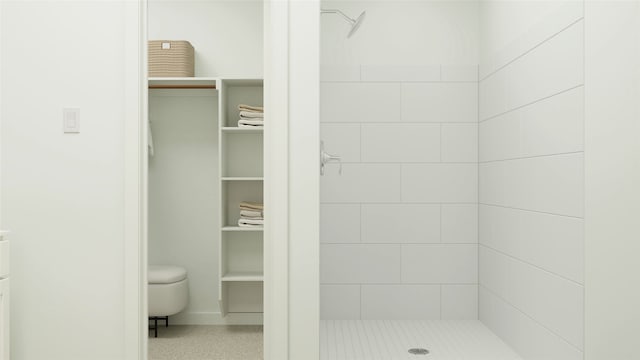 bathroom with toilet and a tile shower