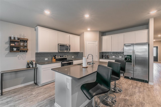 kitchen with a kitchen island with sink, sink, white cabinets, and stainless steel appliances