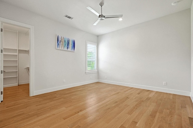 unfurnished bedroom featuring a walk in closet, light wood-type flooring, ceiling fan, and a closet