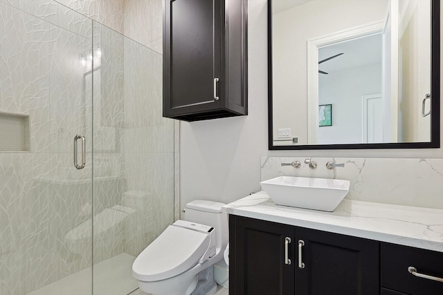 bathroom featuring tasteful backsplash, toilet, vanity, and a shower with shower door