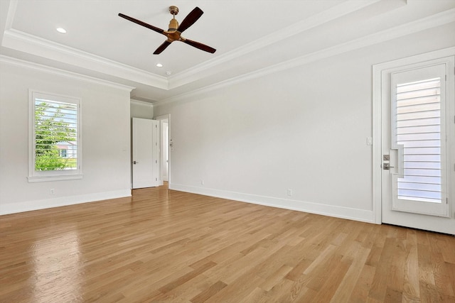 spare room featuring light hardwood / wood-style floors, ceiling fan, a tray ceiling, and crown molding