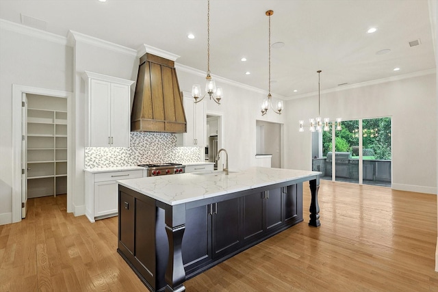 kitchen with sink, white cabinetry, a spacious island, custom exhaust hood, and pendant lighting