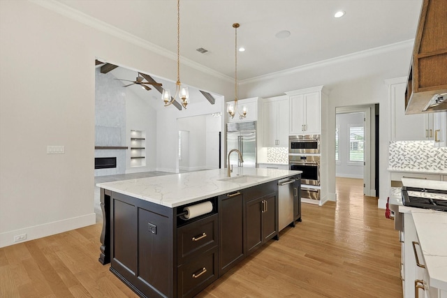 kitchen featuring white cabinets, a kitchen island with sink, appliances with stainless steel finishes, and tasteful backsplash