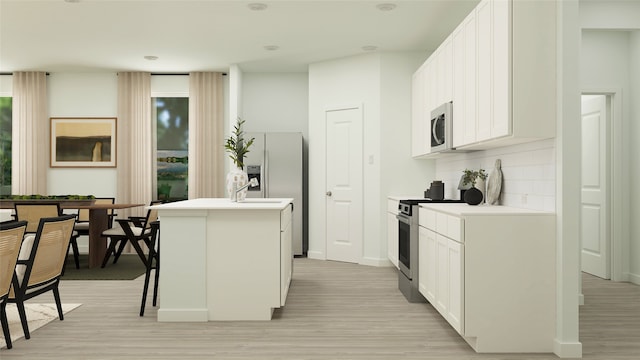 kitchen featuring decorative backsplash, appliances with stainless steel finishes, a kitchen island with sink, light hardwood / wood-style flooring, and white cabinetry